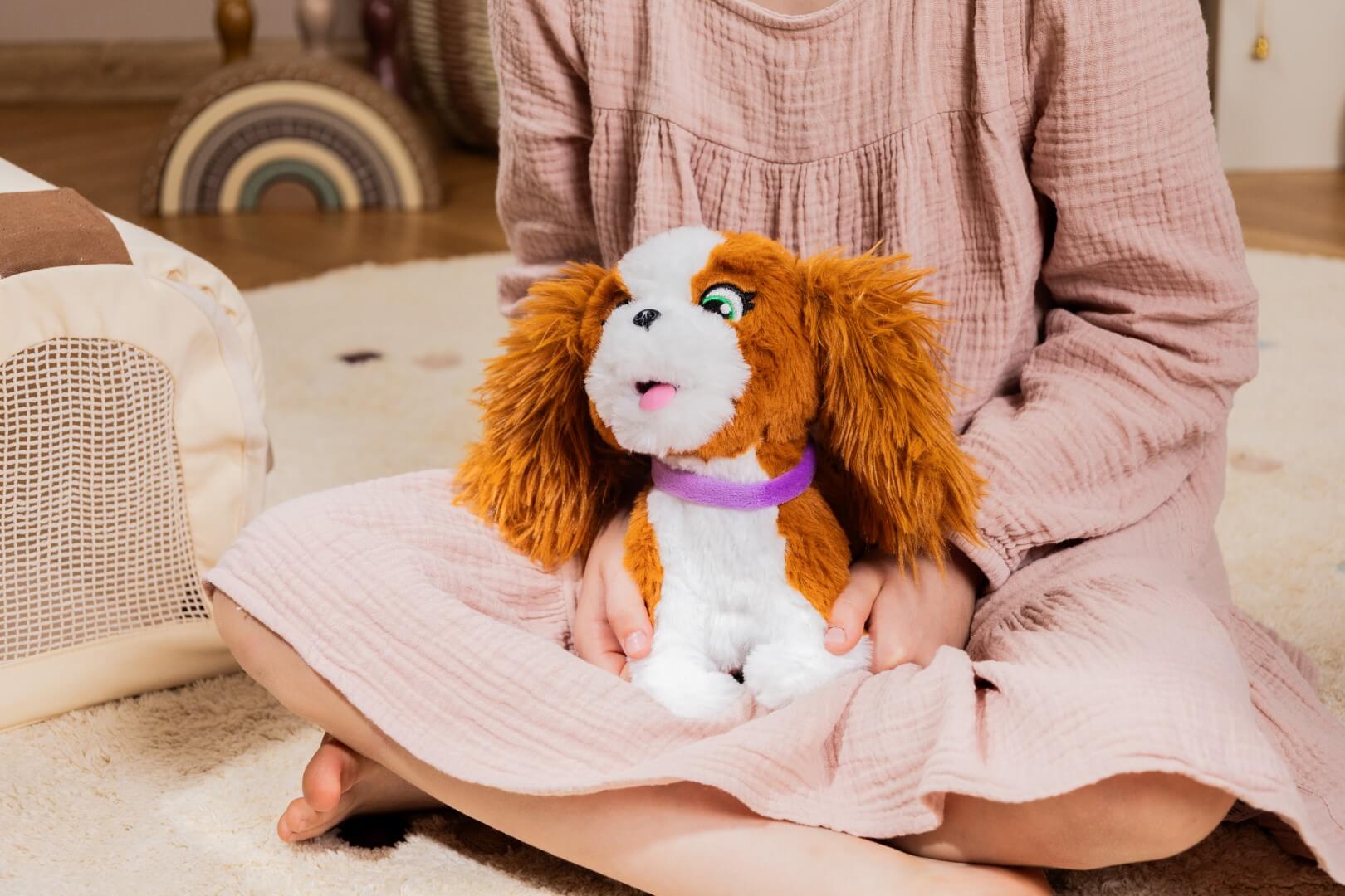 Dziecko trzyma interaktywnego pieska Puppy Luv Bella na kolanach