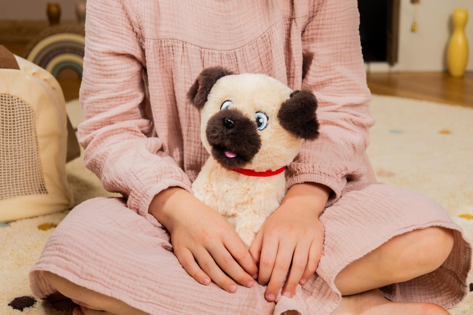 Dziecko trzyma interaktywnego pieska Puppy Luv Cookie na kolanach