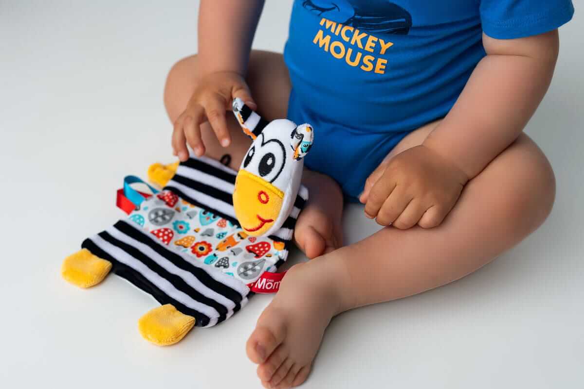 Niemowlę bawiące się szmatką Zebra – ćwiczenie chwytania i motoryki małej